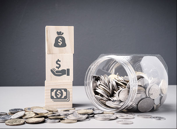 Transparent coin jar next to three 3d wooden cubes