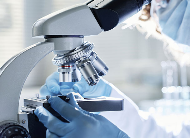 Pessoa utilizando microscópio dentro de laboratório